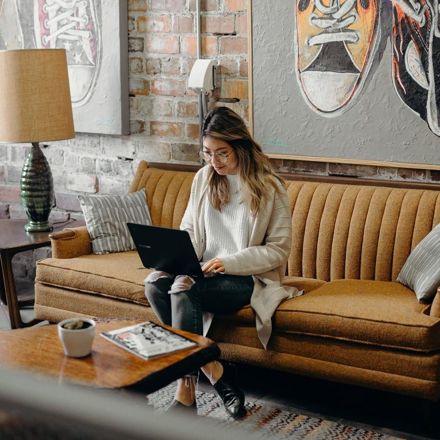 a woman sitting on a couch working on a laptop